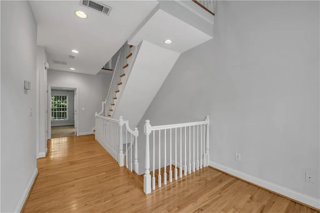 Staircase featuring white balusters and wood treads, complemented by wood-finish flooring throughout the hall