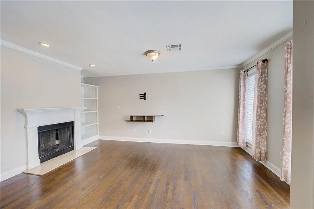 Unfurnished living room featuring dark hardwood / wood-style floors and ornamental molding