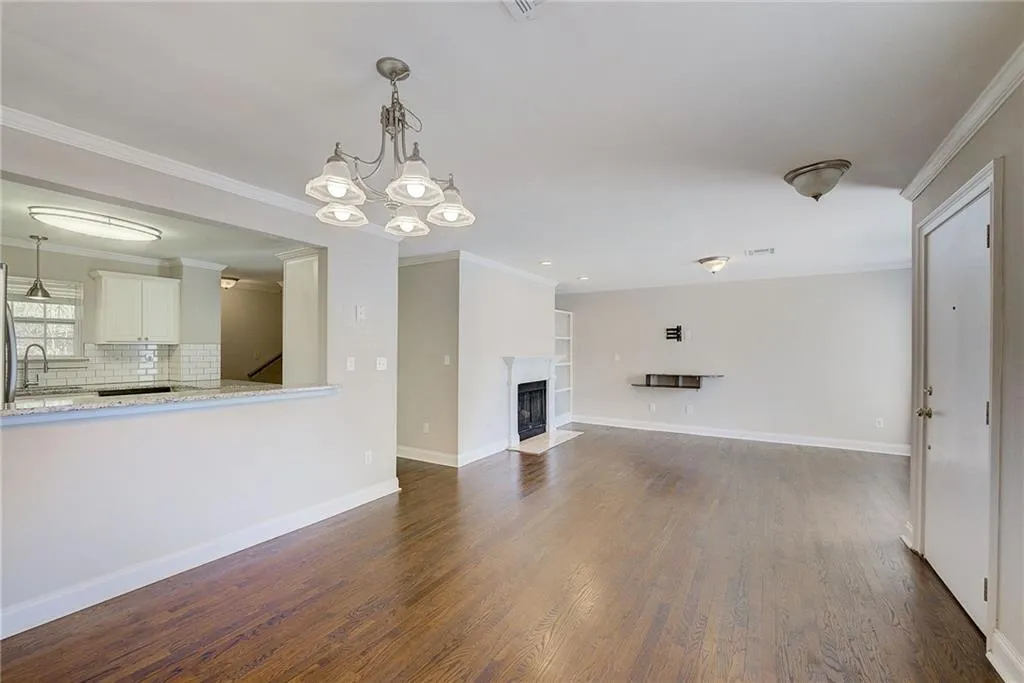 Unfurnished living room with crown molding, dark hardwood / wood-style flooring, a notable chandelier, and sink