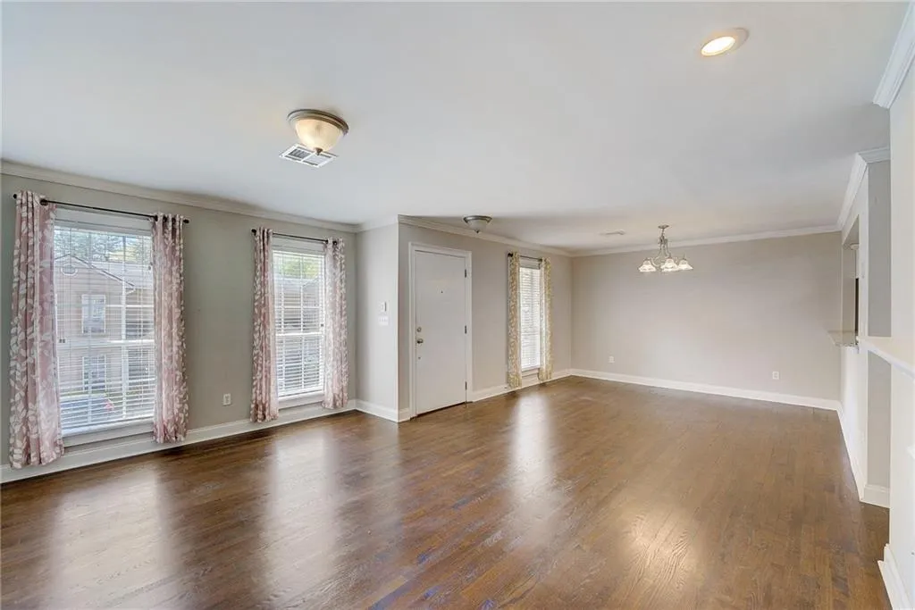 Unfurnished room with crown molding, a notable chandelier, and dark hardwood / wood-style flooring