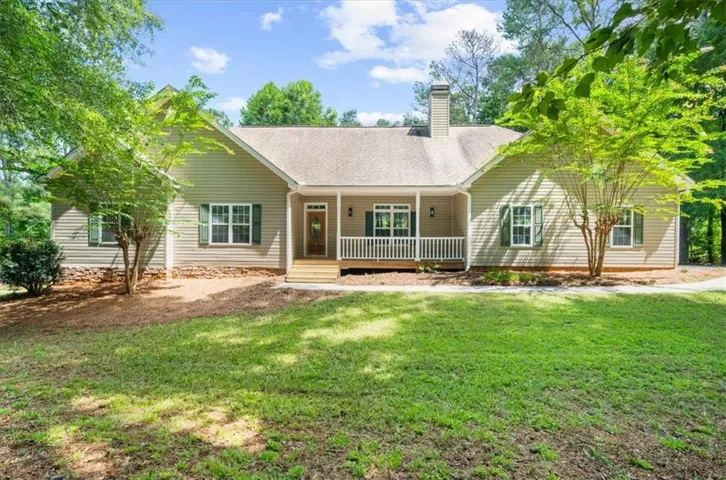 Ranch-style residence featuring a covered front porch, light-colored siding, and a shingle roof