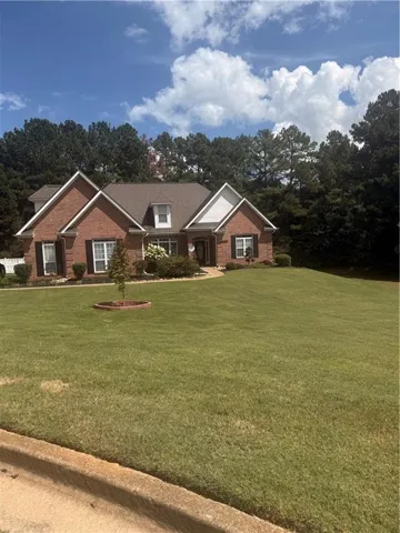 Brick exterior with white gables, dark shutters, dormer window, and mature landscaping