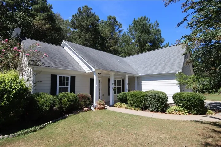Exterior featuring light-colored siding, dark shutters, an attached garage, and a covered entry