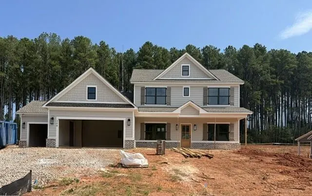 Two-story residence featuring light gray siding, dark gray shutters, a covered entry porch, and an attached two-car garage