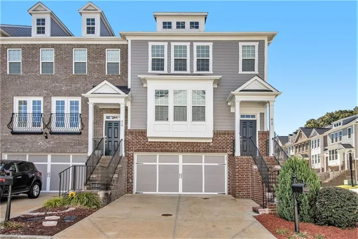 Brick and siding exterior with multiple dormer windows, individual entry porches, and integrated garage spaces
