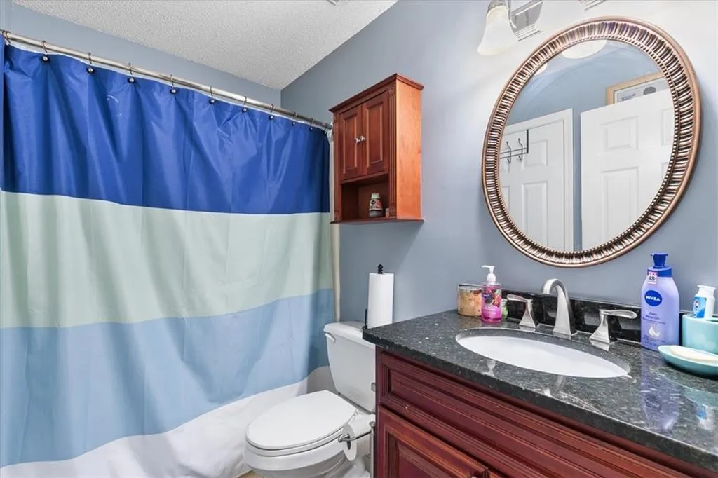 Bathroom featuring vanity with extensive cabinet space, toilet, and a textured ceiling