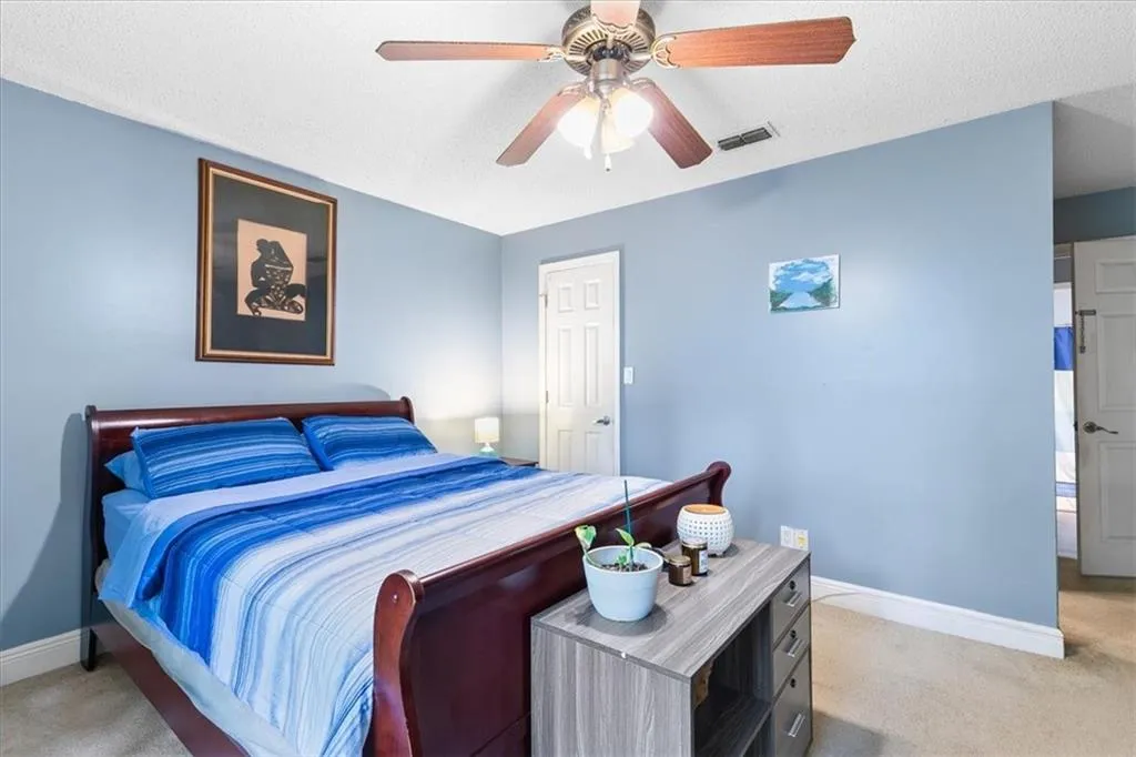 Carpeted bedroom with a textured ceiling and ceiling fan