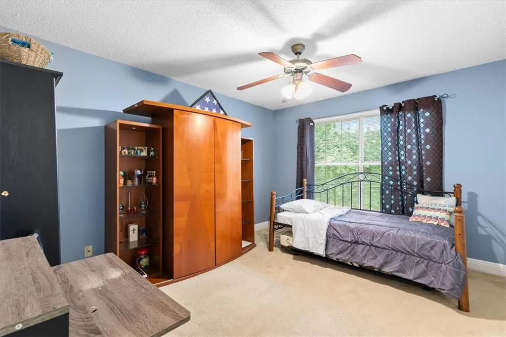 Bedroom with a textured ceiling, carpet floors, and ceiling fan