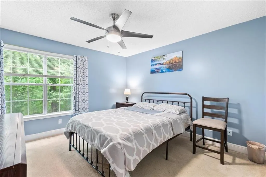 Carpeted bedroom featuring ceiling fan and a textured ceiling