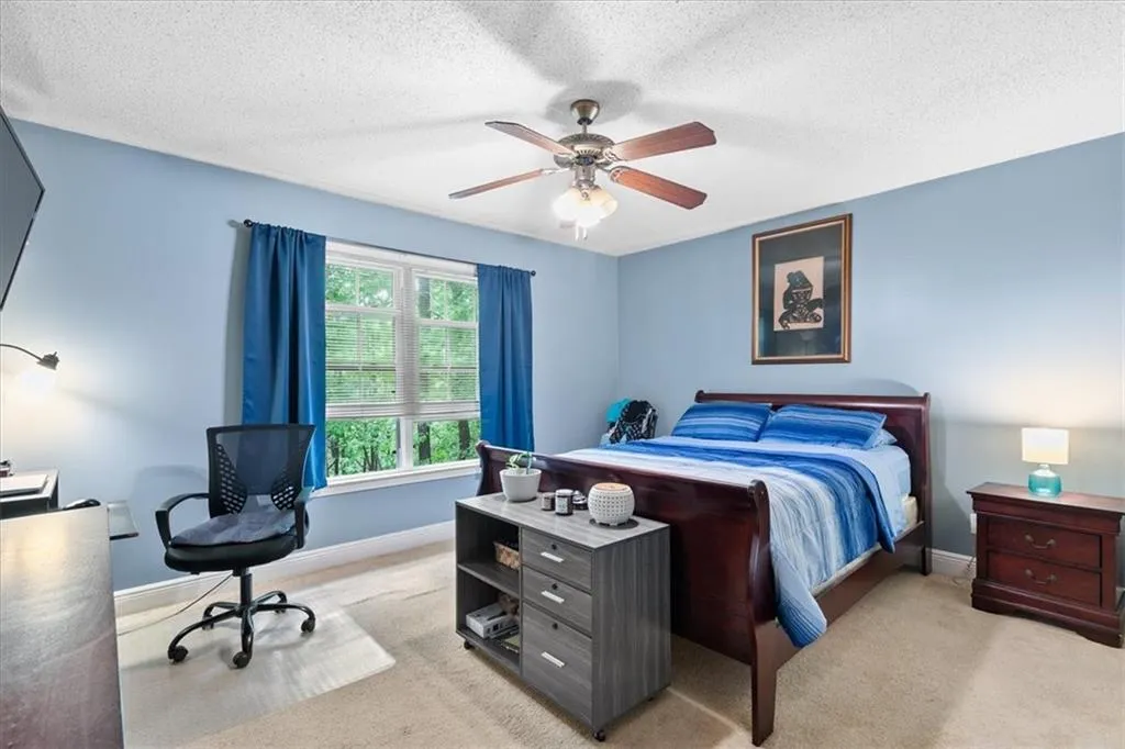Carpeted bedroom featuring ceiling fan and a textured ceiling