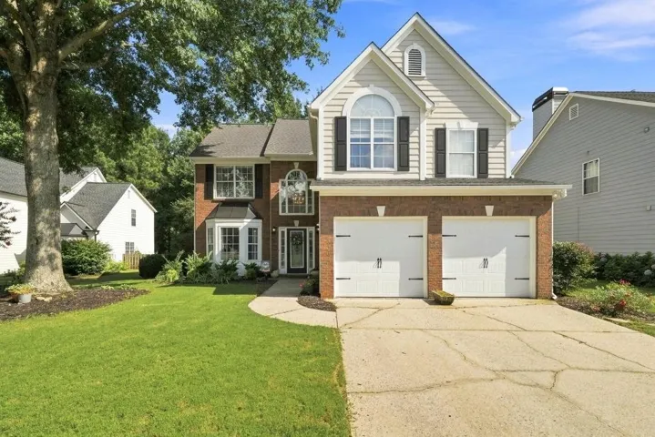Brick and siding exterior with a two-car garage, arched window, and bay window