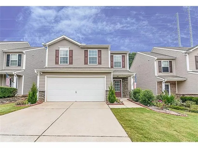 Two-story residence featuring siding exterior, an attached garage, and a concrete driveway