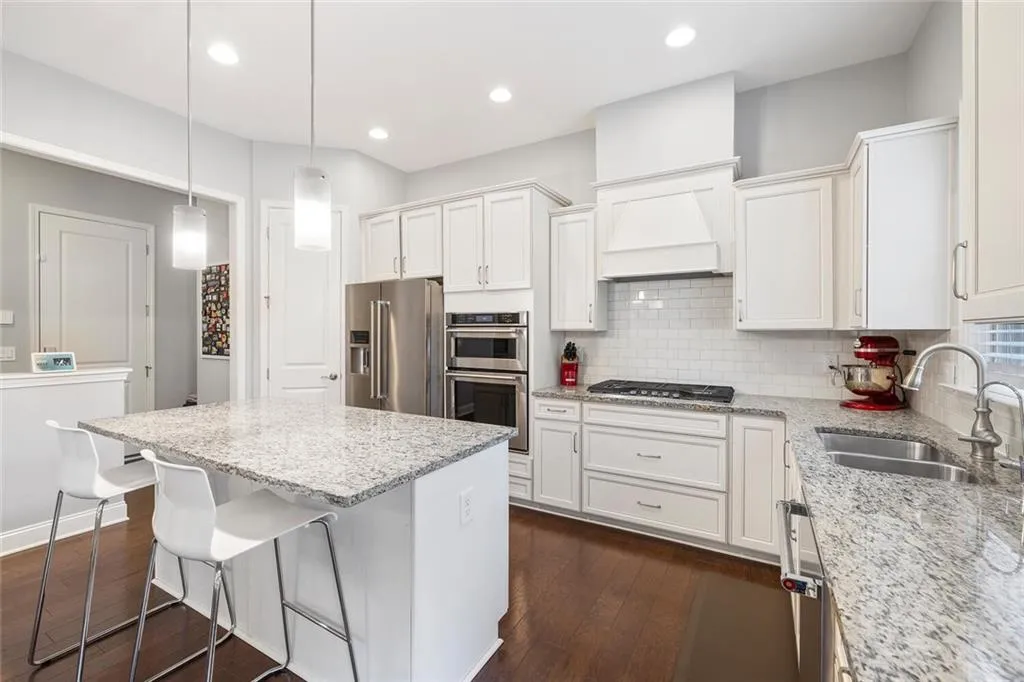 Kitchen with a kitchen island, hardwood flooring, appliances with stainless steel finishes, sink, and tasteful backsplash