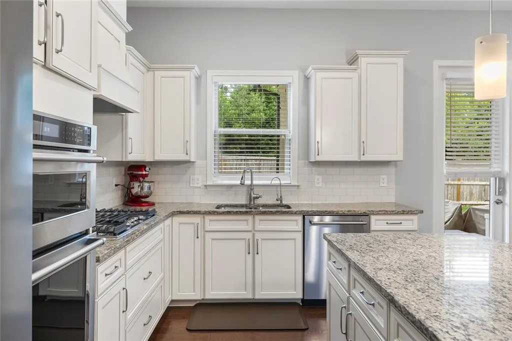 Kitchen with stainless steel appliances, decorative light fixtures, Hardwood flooring, backsplash, and sink