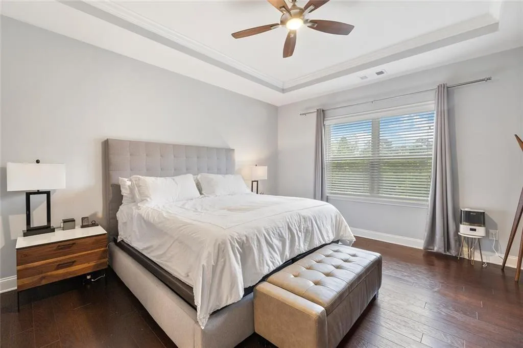 Bedroom featuring  hardwood floors, ceiling fan, tray ceiling, and crown molding