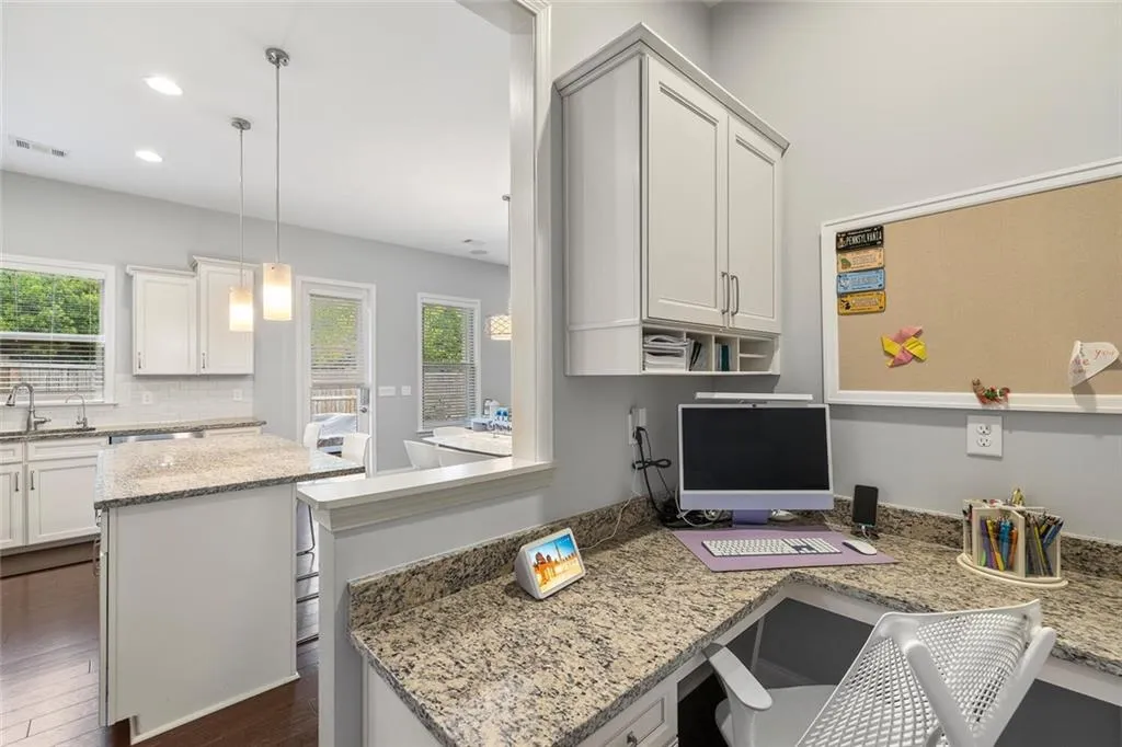 Kitchen featuring hanging light fixtures, light stone countertops, a center island, and hardwood flooring