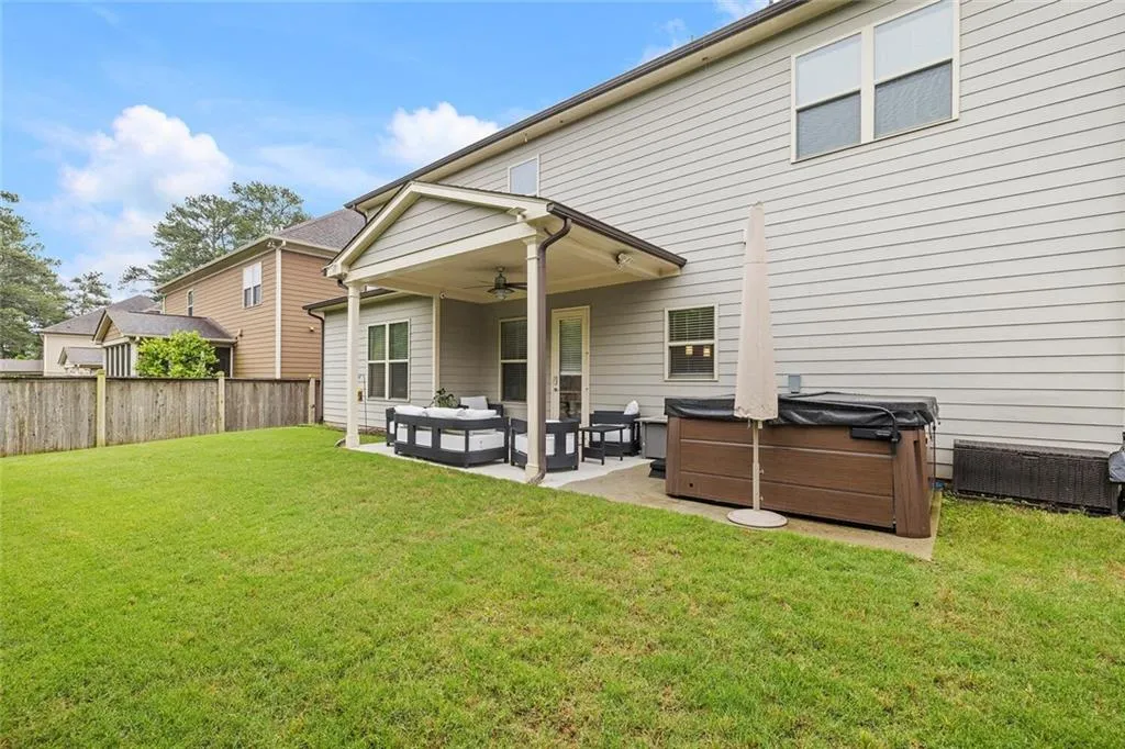Back of property with a patio, a yard, a hot tub, and ceiling fan