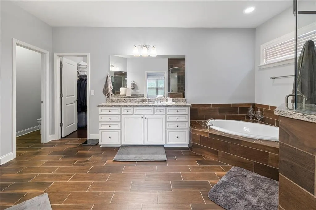 Bathroom featuring tile flooring, a relaxing tiled bath, and vanity