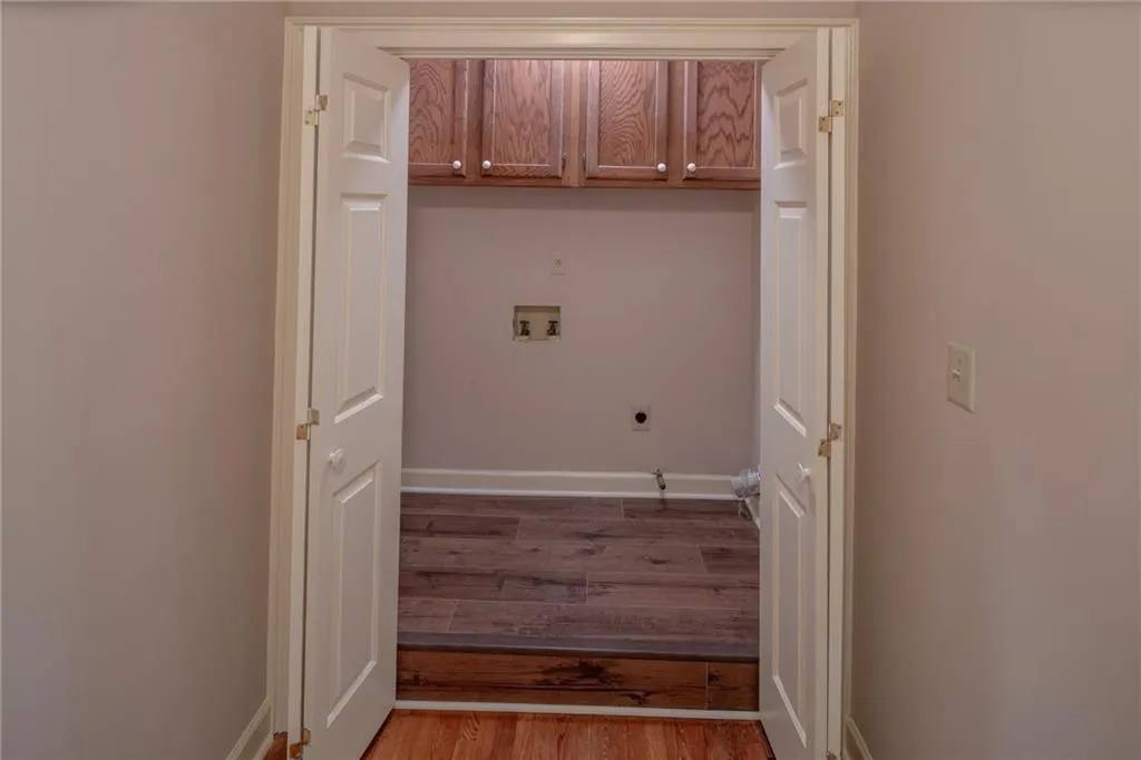 Clothes washing area featuring electric dryer hookup, wood-type flooring, cabinets, and hookup for a washing machine