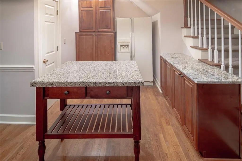 Kitchen featuring white fridge with ice dispenser, light hardwood / wood-style flooring, and light stone counters