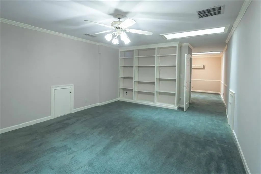 Unfurnished bedroom with ornamental molding, ceiling fan, and dark carpet