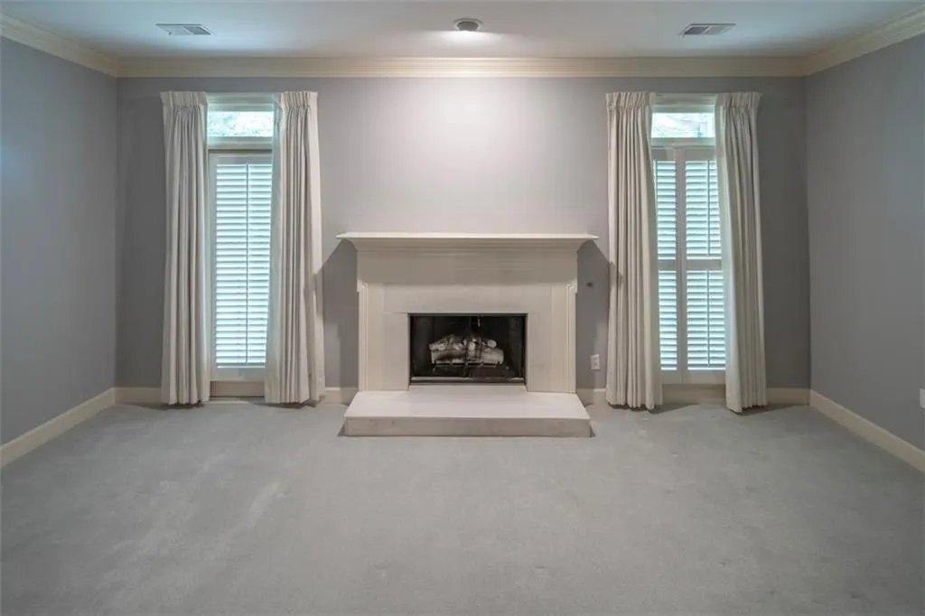 Unfurnished living room featuring crown molding, a healthy amount of sunlight, and carpet flooring