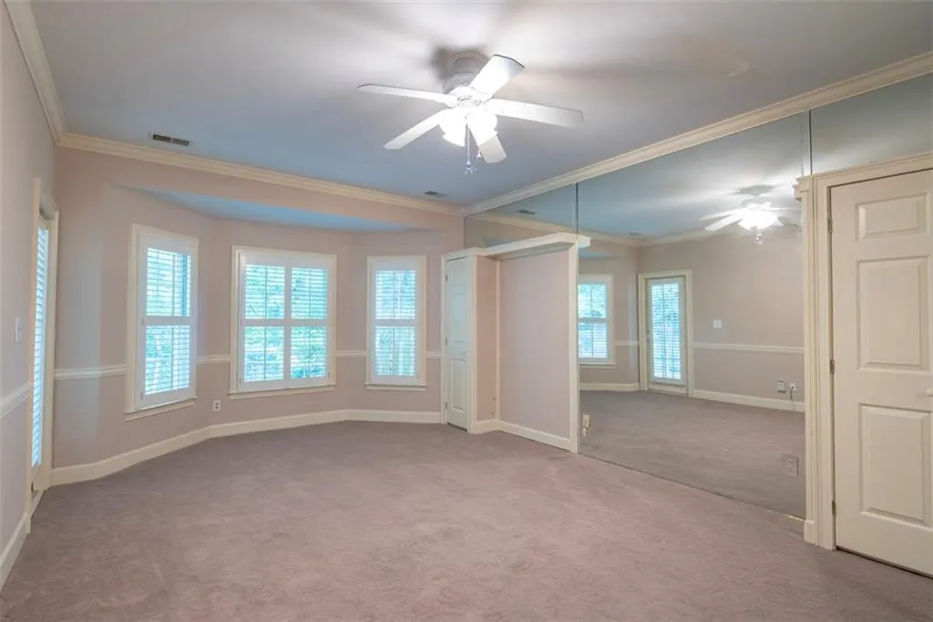 Unfurnished bedroom featuring ornamental molding, ceiling fan, and carpet floors