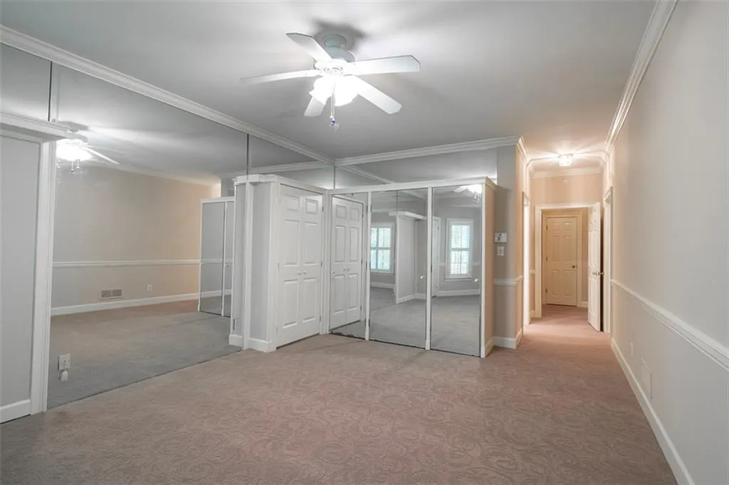 Unfurnished bedroom with ornamental molding, ceiling fan, and carpet flooring