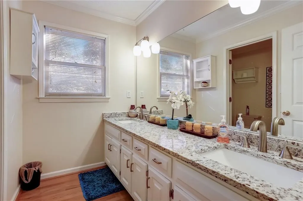 Bathroom featuring wood-type flooring, dual sinks, a healthy amount of sunlight, and vanity with extensive cabinet space