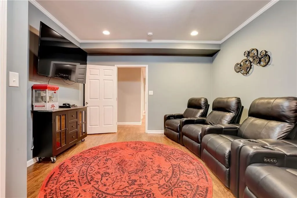Cinema featuring ornamental molding and light hardwood / wood-style flooring