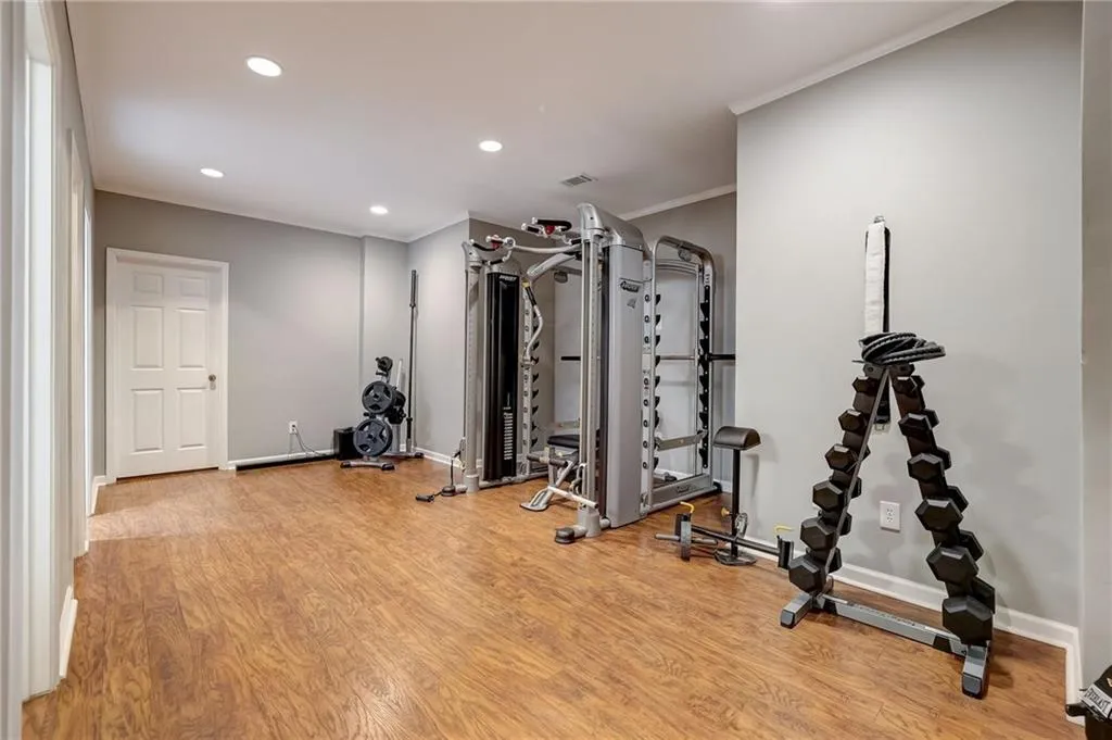 Exercise room with light wood-type flooring and ornamental molding