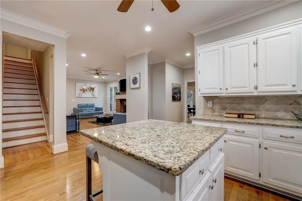 Kitchen featuring light hardwood / wood-style floors, backsplash, white cabinets, and ceiling fan