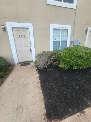 Front entry featuring a panel door with white trim, an exterior wall light, and a window with white blinds