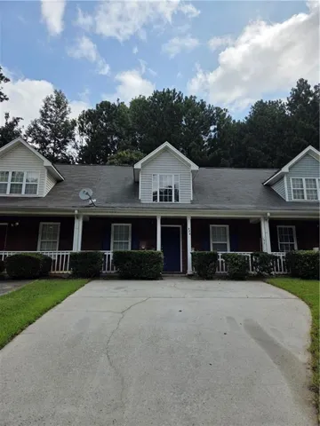 Traditional-style residence featuring a brick facade with light-colored siding accents and three dormer windows