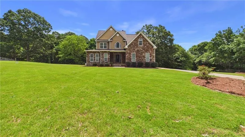 Stately two-story residence with stone and siding facade, gabled rooflines, and multiple windows