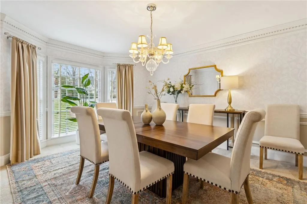 Dining area featuring a chandelier, wallpapered walls, and crown molding