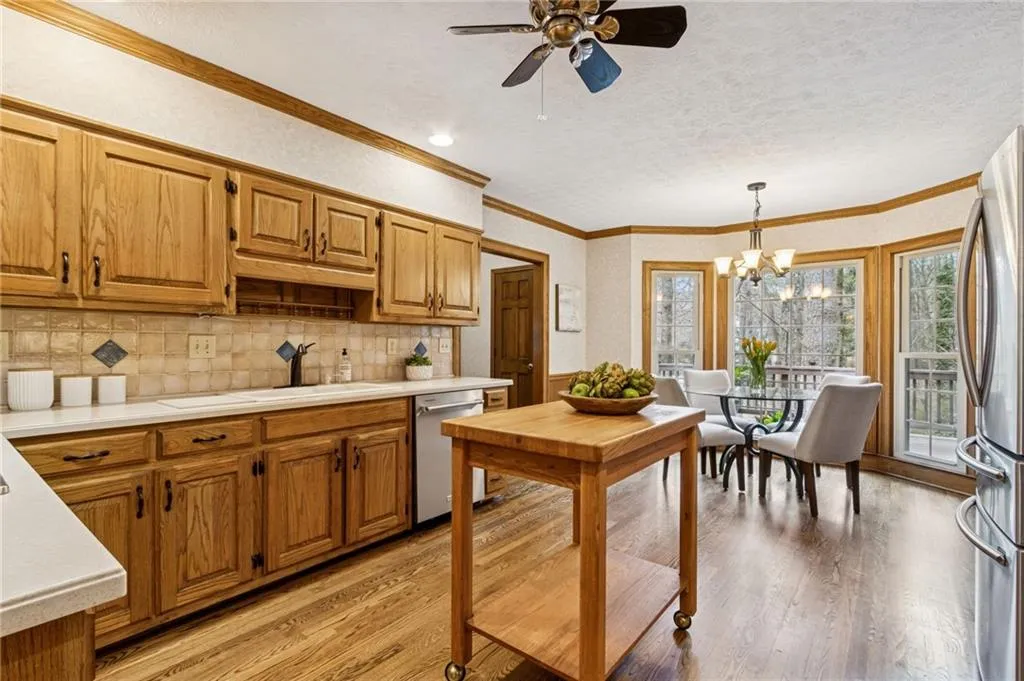 Kitchen with a ceiling fan, light countertops, wood finish cabinetry, stainless steel appliances, and light wood-style flooring