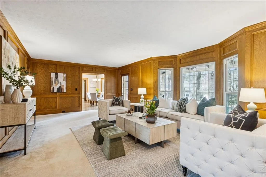 Carpeted family room featuring wooden walls, and crown molding