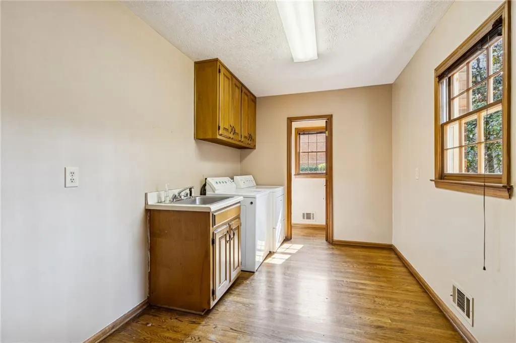 Laundry area featuring light wood-style floors, cabinet space, a textured ceiling, and washing machine and dryer