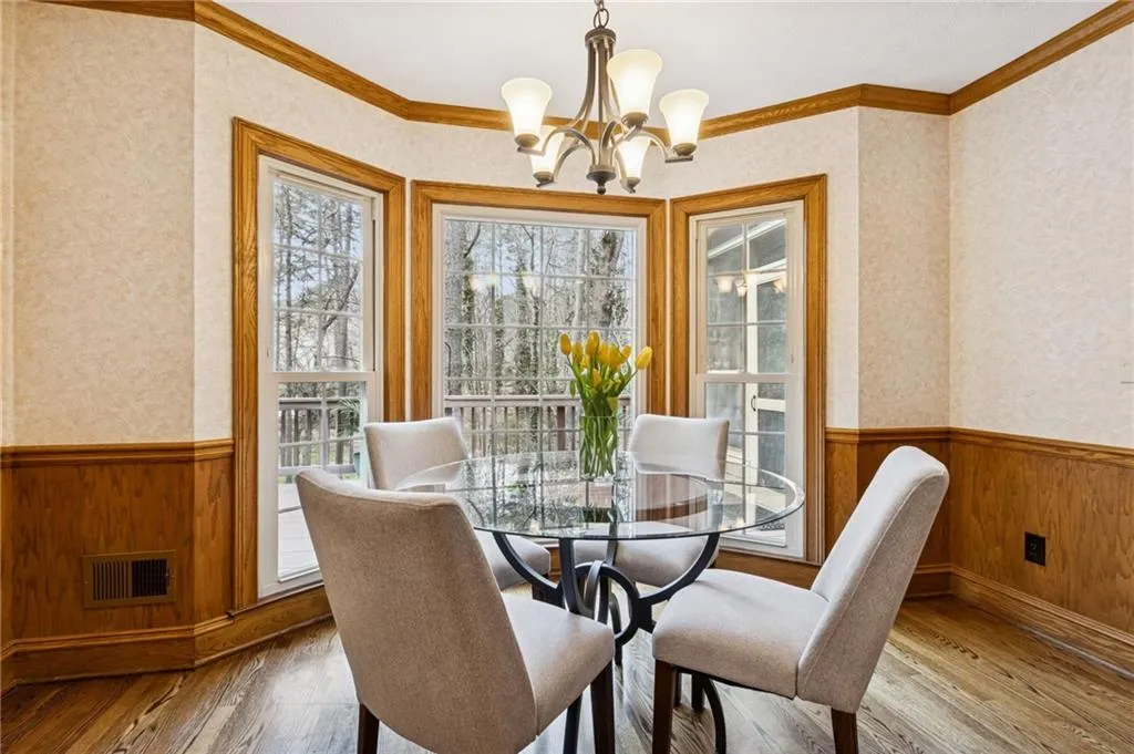 Dining room featuring wood walls, wainscoting, wallpapered walls, a chandelier, and crown molding