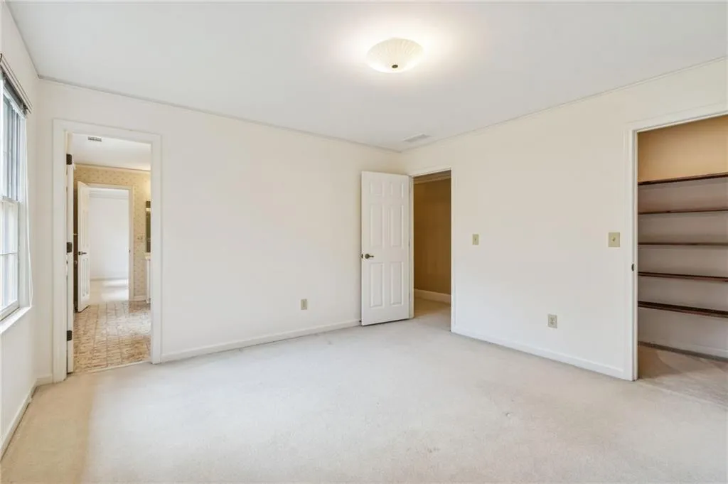 Unfurnished bedroom with light carpet and a walk in closet