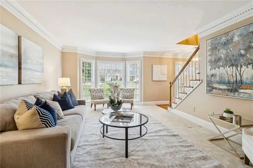 Carpeted living room featuring stairs and ornamental molding