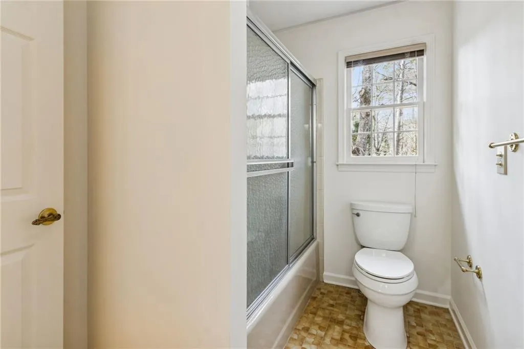 Full bathroom with toilet and bath / shower combo with glass door