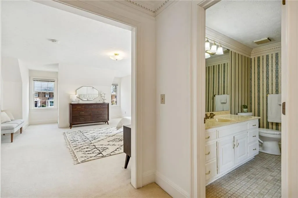 Bathroom with vanity, ensuite bathroom, light carpet, wallpapered walls, and healthy amount of natural light