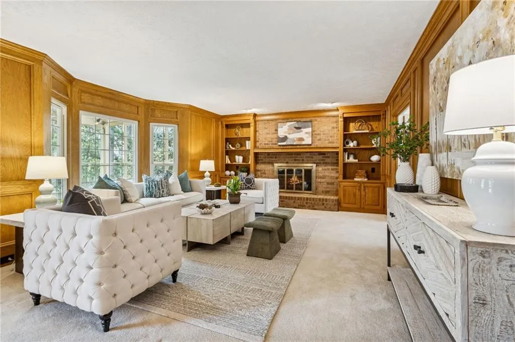 Living area with built in features, light carpet, a brick fireplace, and ornamental molding
