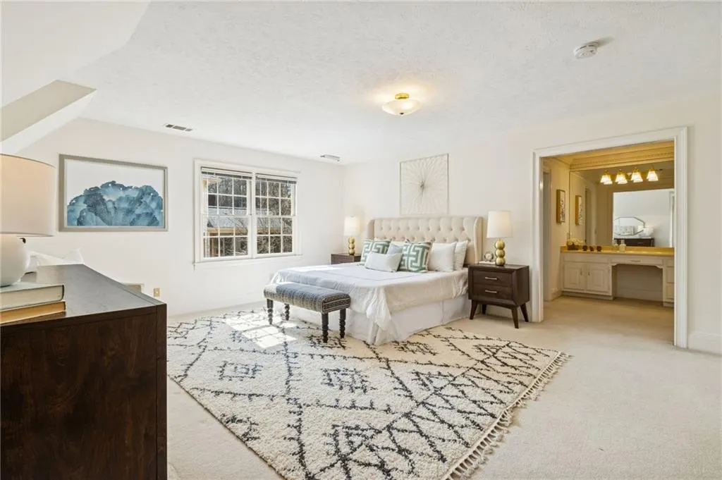 Bedroom with light colored carpet, a textured ceiling, an office area, and connected bathroom