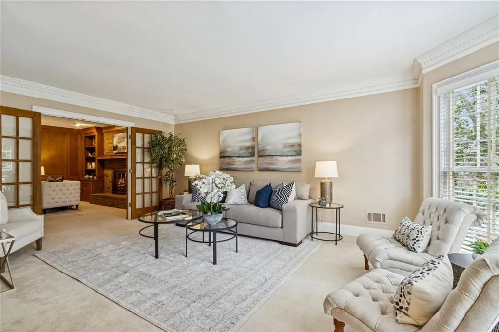 Carpeted living room with ornamental molding and baseboards