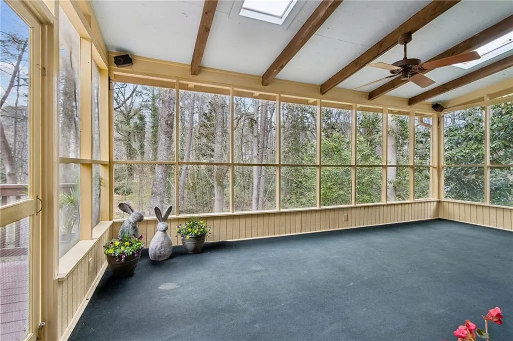 Unfurnished sunroom with a skylight, carpet floors, lofted ceiling with beams, and plenty of natural light