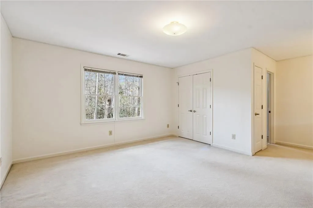 Unfurnished bedroom featuring light carpet and a closet