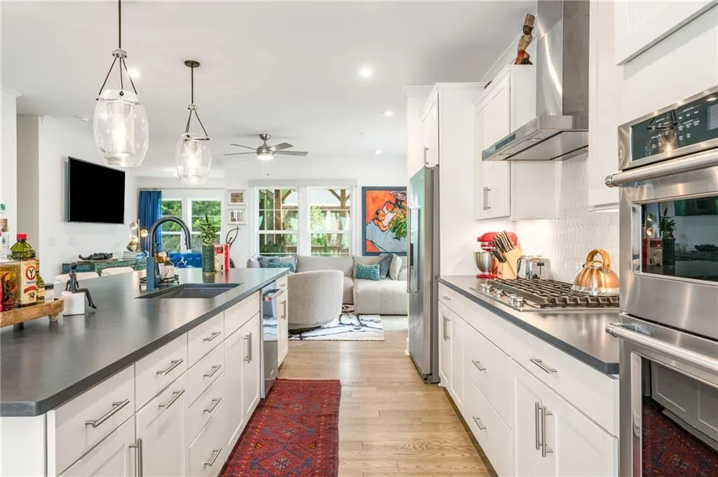 Kitchen featuring open floor plan, stainless steel appliances, dark countertops, light wood finished floors, and recessed lighting